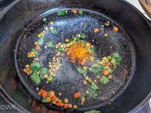 Adding salt and turmeric powder and stiring it before adding the cooked sevai