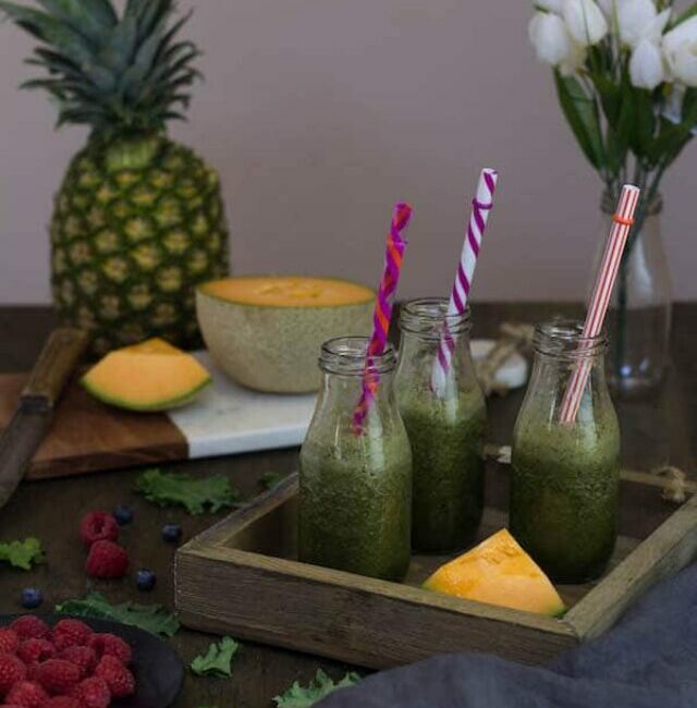 Kale Smoothie with Berries with colorful straws in the jars