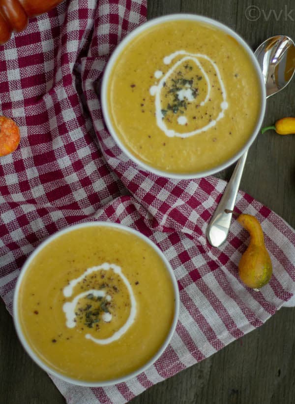 butternut squash soup in two bowls with a swirl of coconut milk and oregano