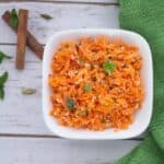 Carrot Coconut Salad or Carrot Kosambari served in a white bowl with two cinnamon sticks below it