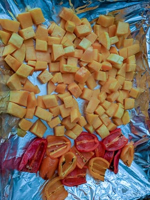 Bell peppers and butternut squash in a baking tray lined with aluminium foil