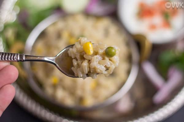 A spoonful of brown rice with corn and peas