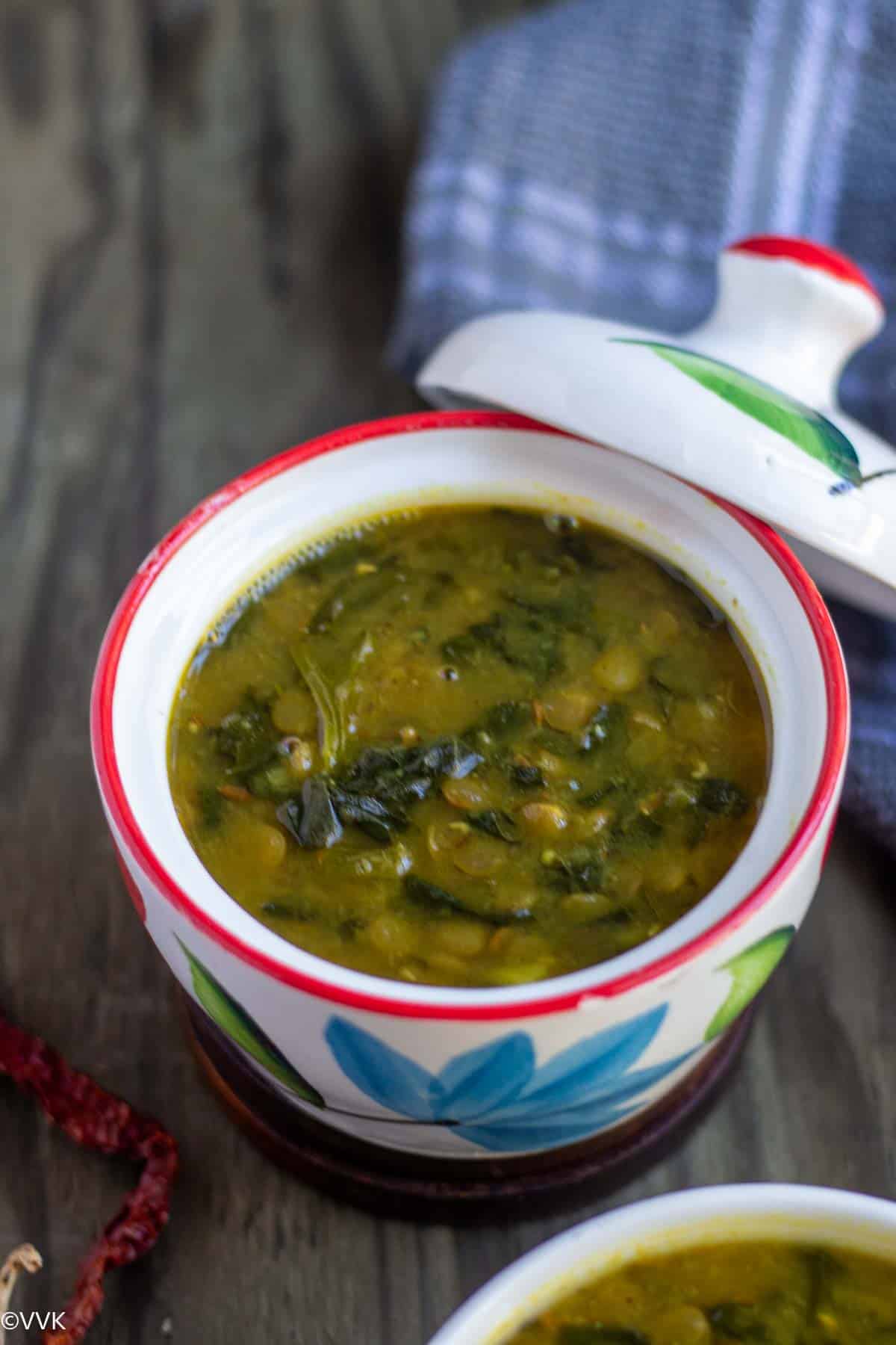 close up shot dal palak with green lentils served in a white ceramic ware