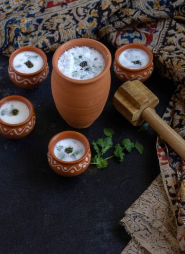neer mor in clay tumbler and with four small clay tumblers around