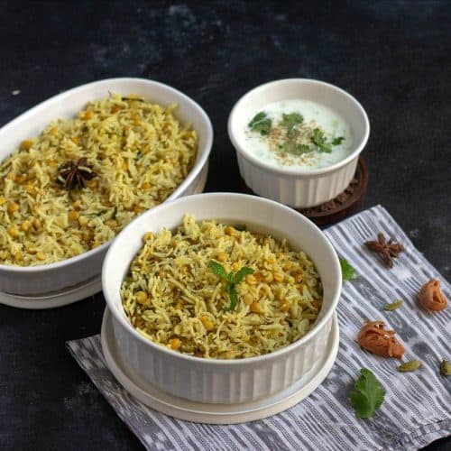 qubooli biryani in white ceramic pot with whole spices on the side