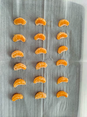 clementine segments on a baking tray lined with parchment paper