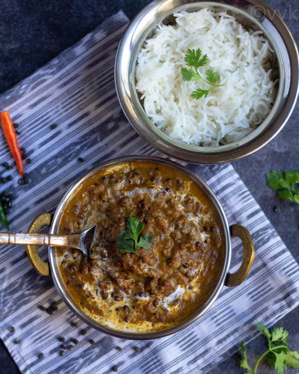 instant pot black lentils curry in a bowl with serving spoon