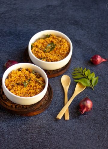 dry coconut chutney in two white bowls with wooden spoons on the side