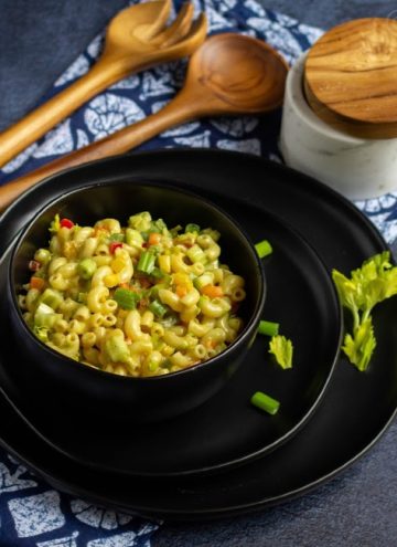 pasta salad on a black bowl placed on a black plate