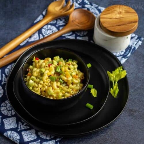 pasta salad on a black bowl placed on a black plate
