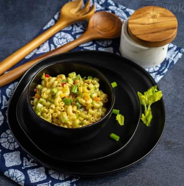 pasta salad on a black bowl placed on a black plate