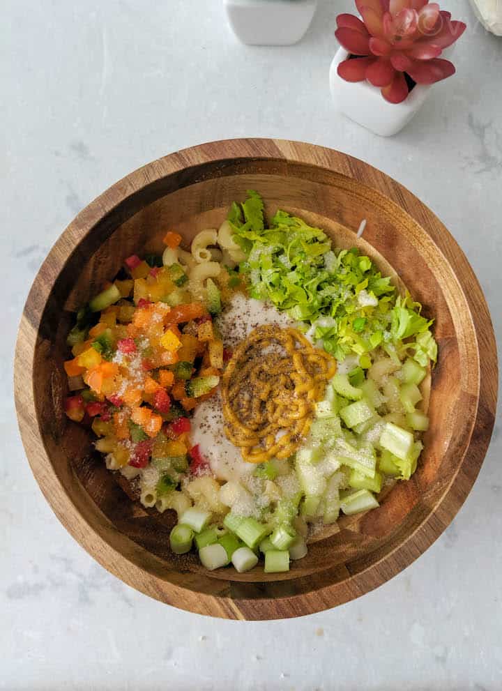 pasta salad with all veggies and sauces before mixing in a wooden bowl