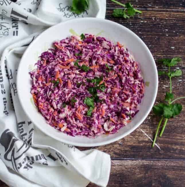 cabbage coleslaw in a bowl with white fabric on the side