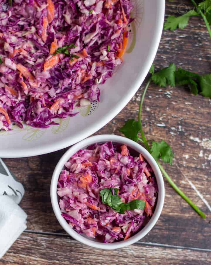 cabbage coleslaw in a small serving bowl and on a white big bowl on the side