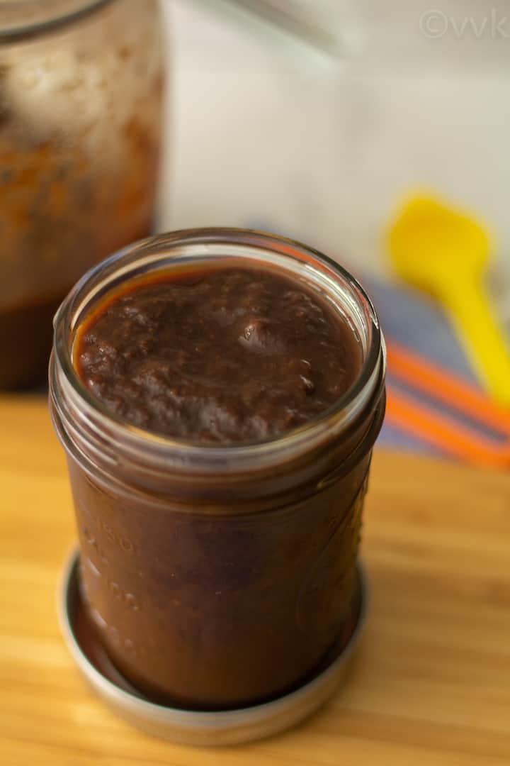 homemade tamarind paste in a glass jar placed on a wooden board