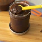homemade tamarind paste in a glass jar placed on a wooden board with yellow spoon on top