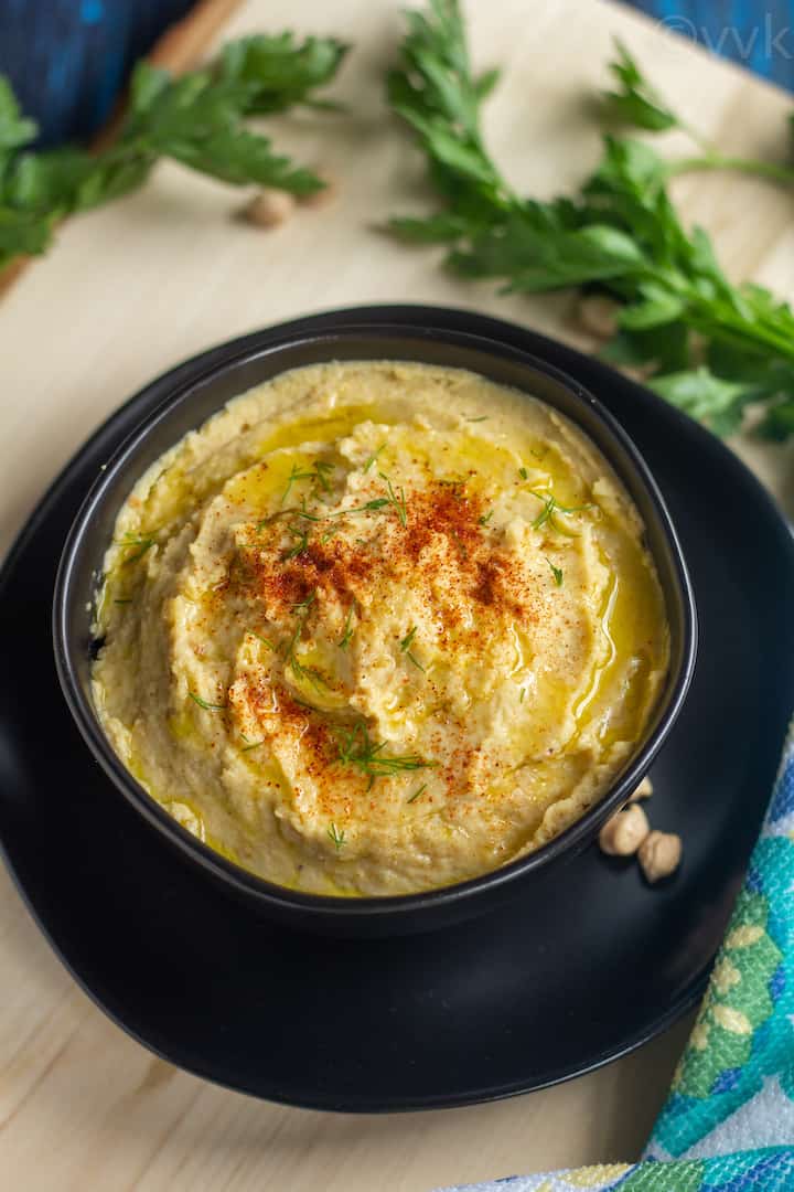 close up shot of homemade hummus served in a black bowl