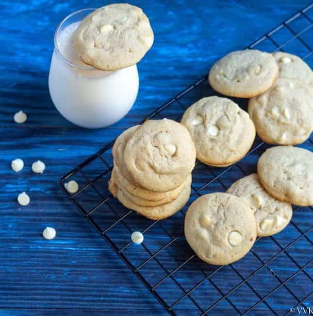 square image of eggless white chocolate chip cookies with macadamia nuts placed on a cooling rack