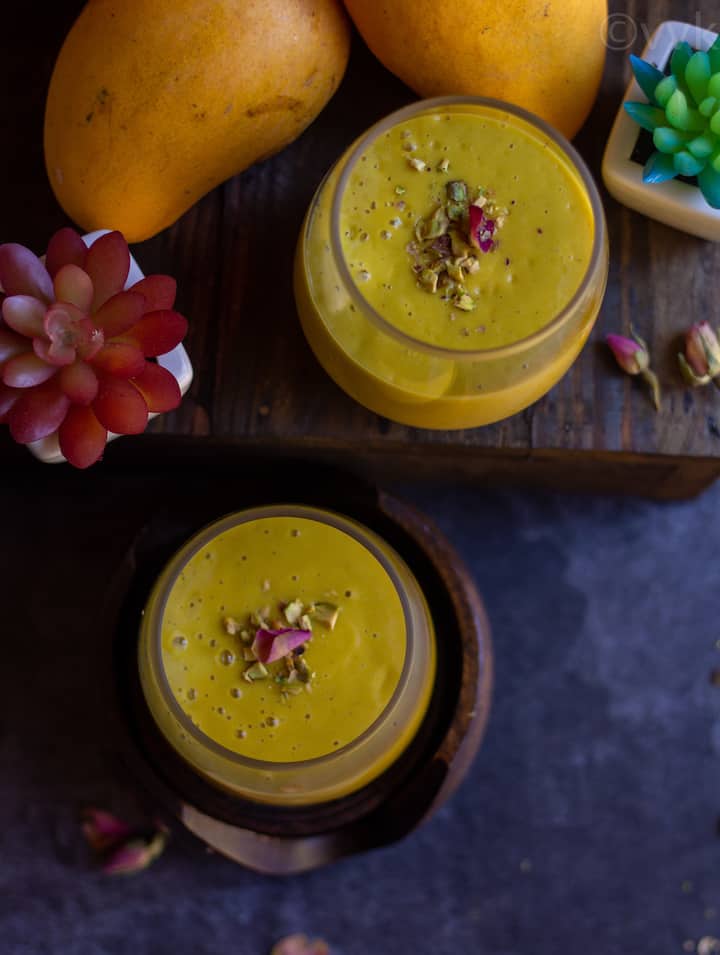 overhead shot of mango lassi with mangoes and succulent on the side as a prop
