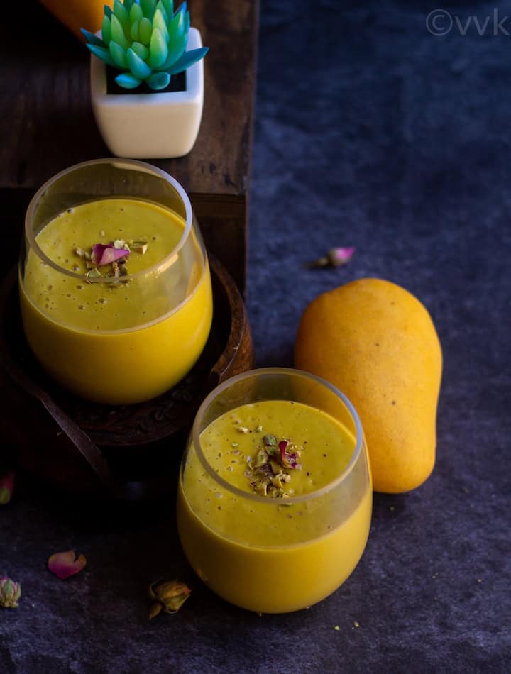 mango lassi in two glass jars with a mango on the side