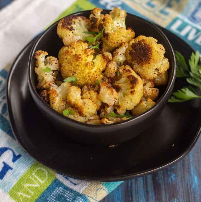 roasted cauliflower in a black bowl with parsley
