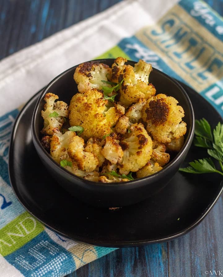 sumac cauliflower in a black bowl served with parsley sprinkled on top