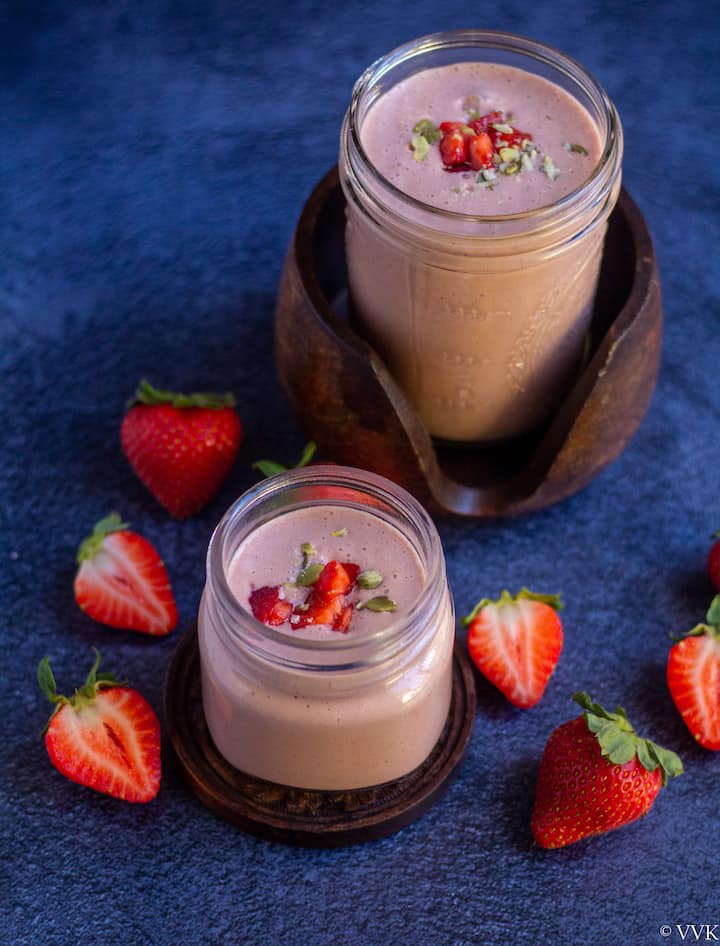strawberry milkshake in masor jars with strawberries around