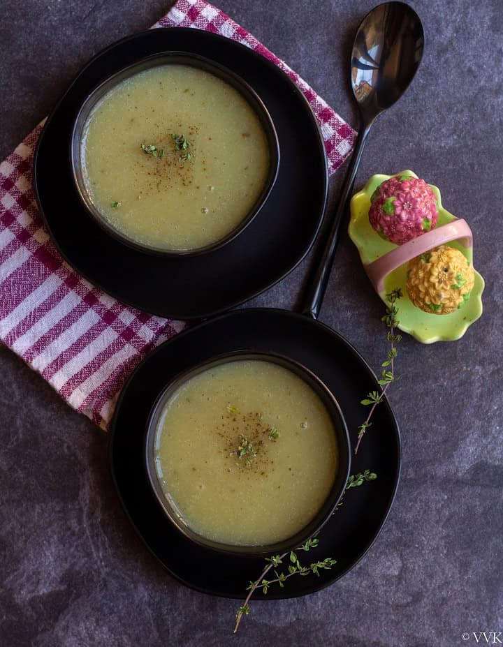 overhead shot of zucchini soup served in black bowls with salt pepper shaker on the side