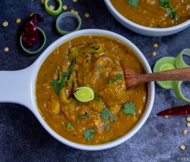 creamy and thick leeks sambar in white bowl with a wooden spoon inside