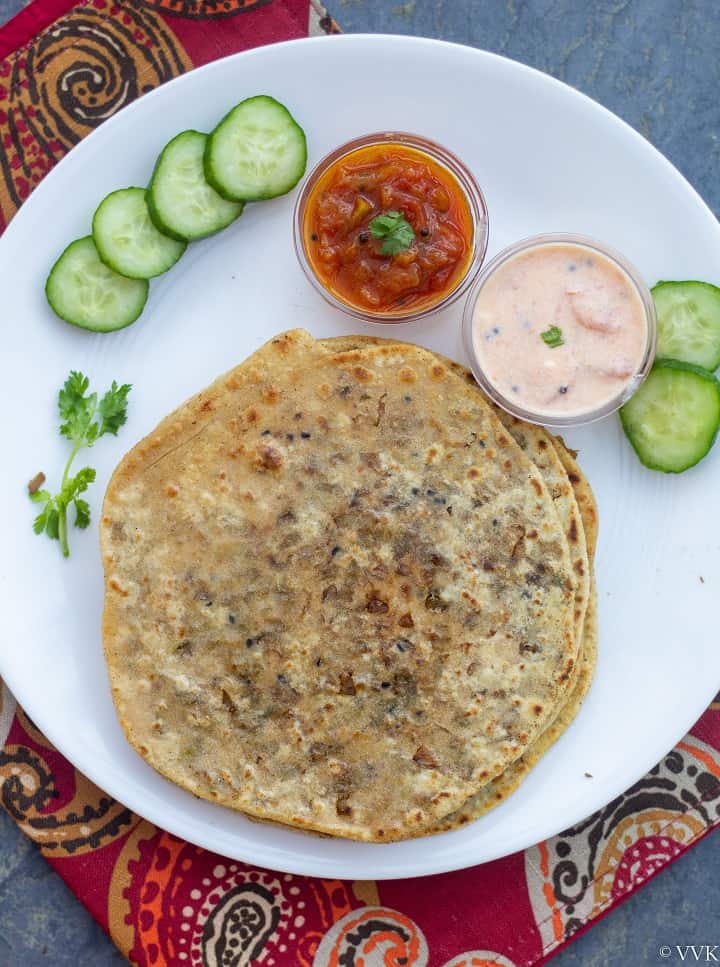 brussels srouts stuffed paratha in white plate with raita and relish and cucumbers on the side