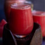 square image of watermelon ginger juice in a glass jar placed on a wooden coasted