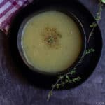 overhead shot of zucchini soup in black bowl with thyme on the side