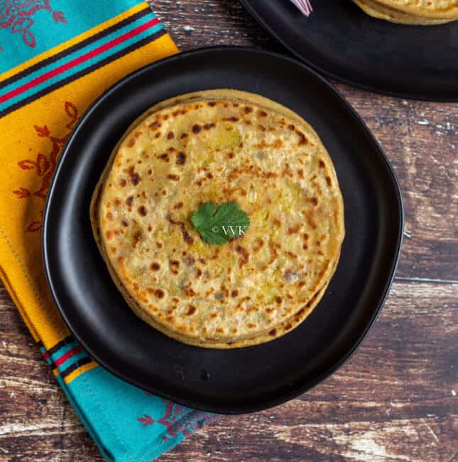 aloo paratha stacked and placed on a black plate