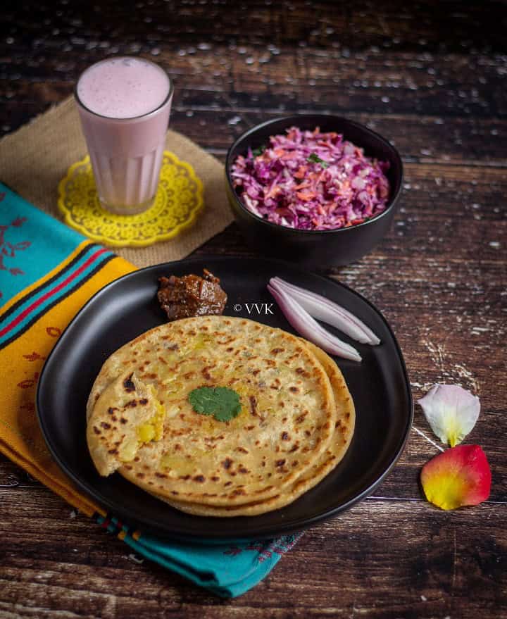 aloo paratha spread with aloo paratha, cabbage coleslaw, lassi and lemon pickle