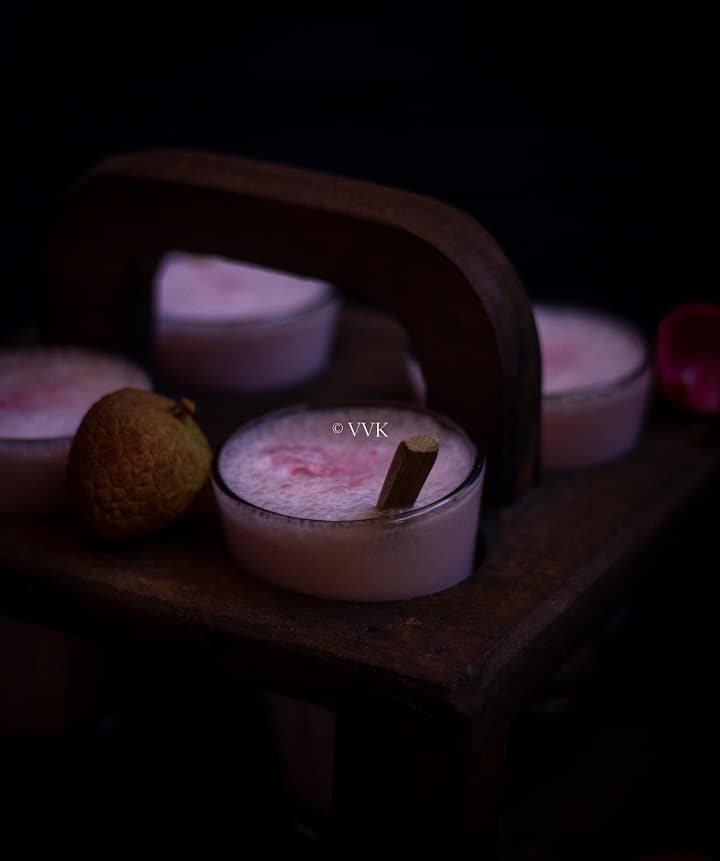 close up shot of lassi placed in tea stand with lychee on the side
