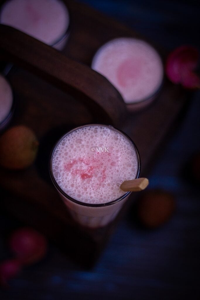 lychee lassi served in tea glass with a wooden spoon on the side