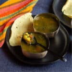 square image of moringa rasam served in two silver ware