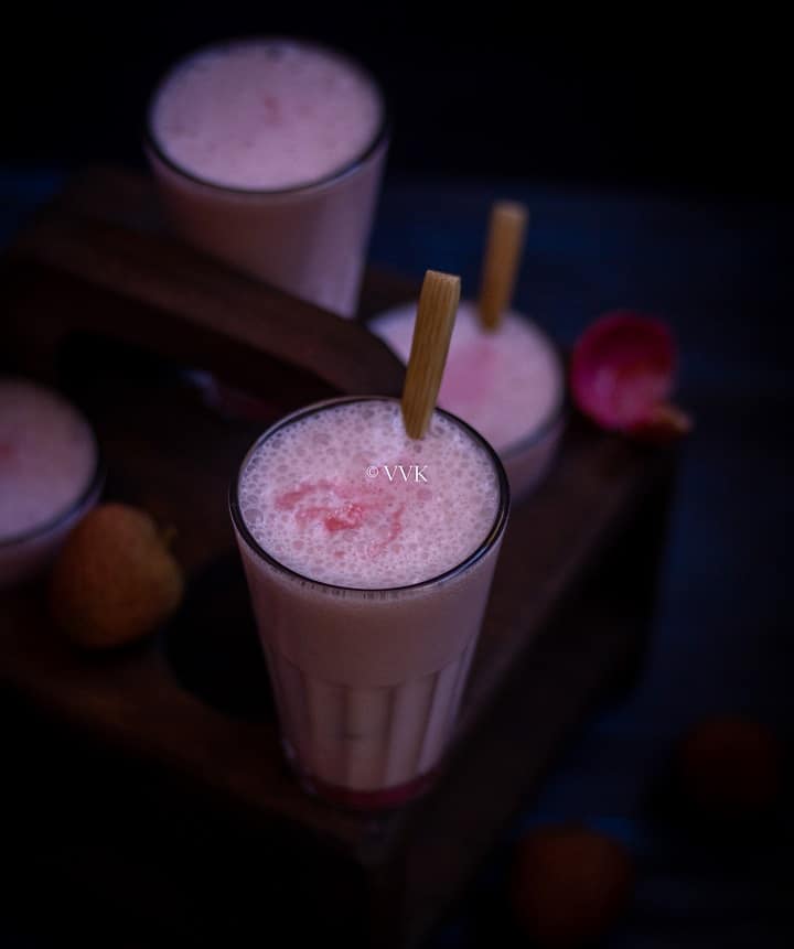 lychee lassi served in tea glass with a wooden spoon on the side