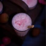 square shot of lychee lassi with wooden spoon inside