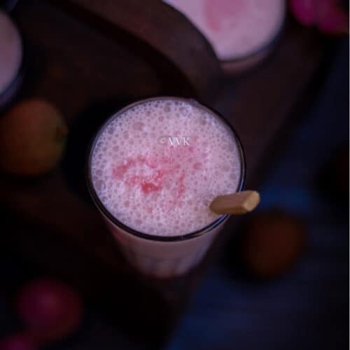 square shot of lychee lassi with wooden spoon inside
