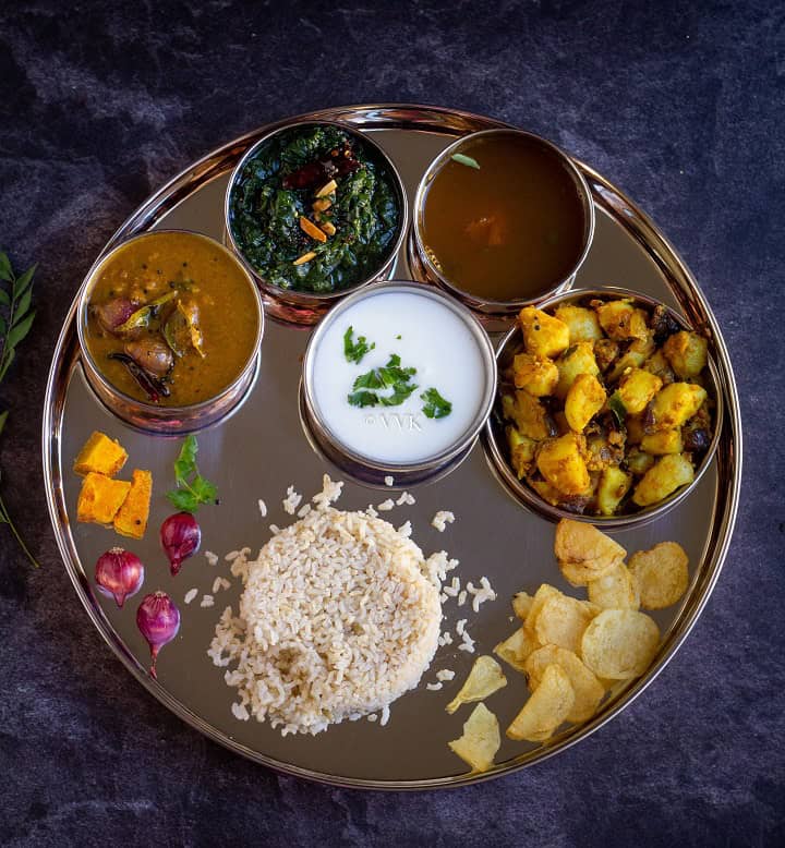 overhead shot of south indian lunch menu with sambar, rasam, kootu and curry