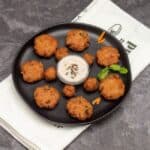 aval vadai or fritters placed on a black plate with chutney