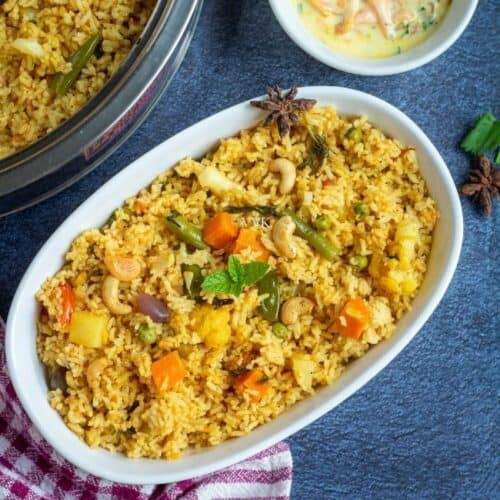 chettinadu kaikari biryani in a white serveware with raita