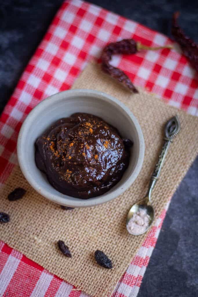 raisin chutney on burlap cloth with some raisins and chili on the side