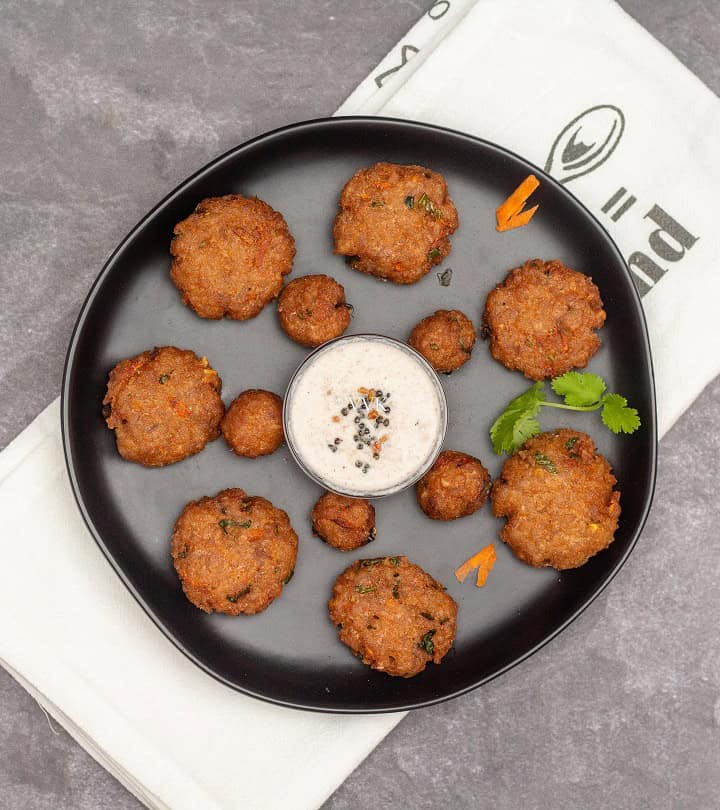 overhead shot of poha vada with coconut chutney in the center served on the black plate