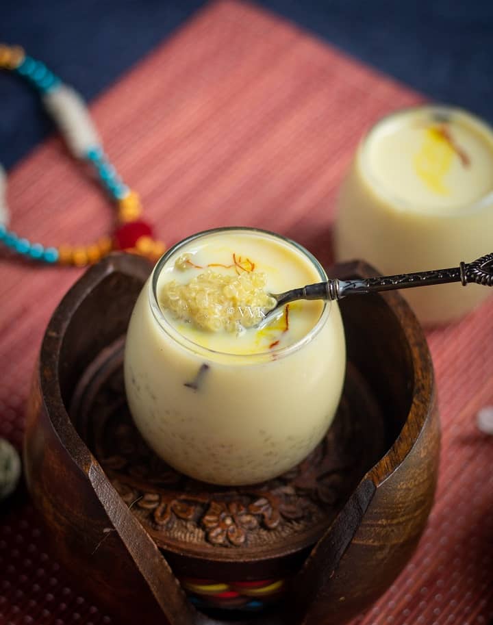 quinoa kheer in a small glass jar with a spoon full of kheerplaced on a wooden coasters