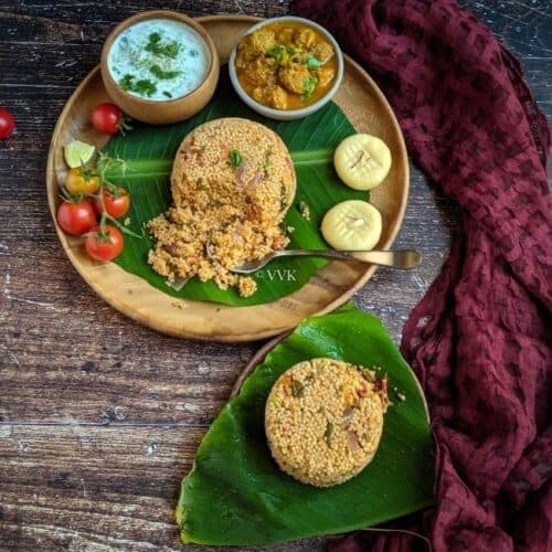 biryani served in a wooden plate lined with banana leaf with raita, gravy and sweet