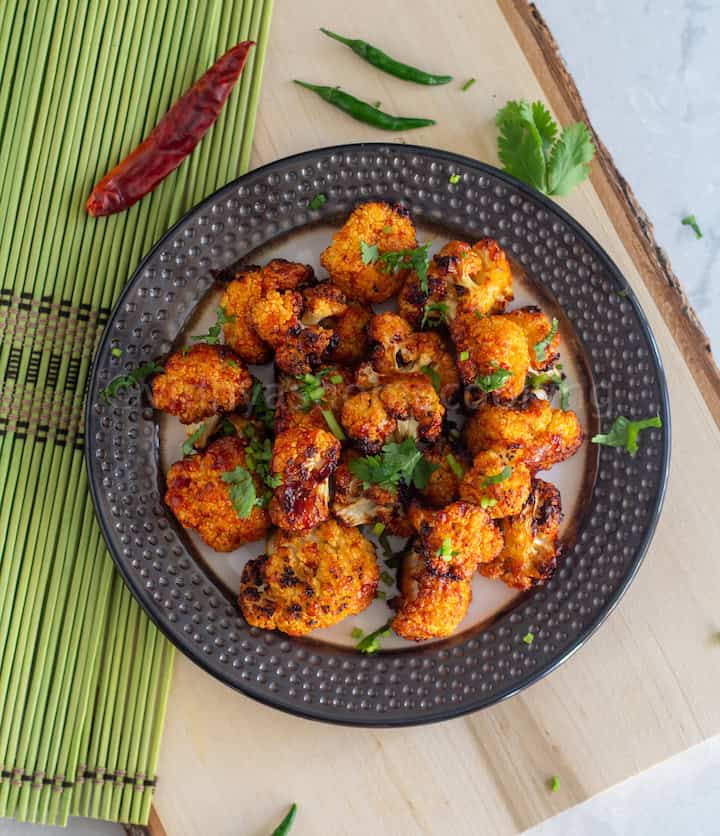 overhead shot of cauliflower bites served on a plate placed on wooden board