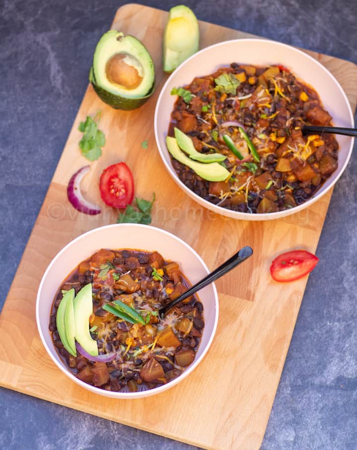 chili sin carne with zucchini served in two bowls with avocado