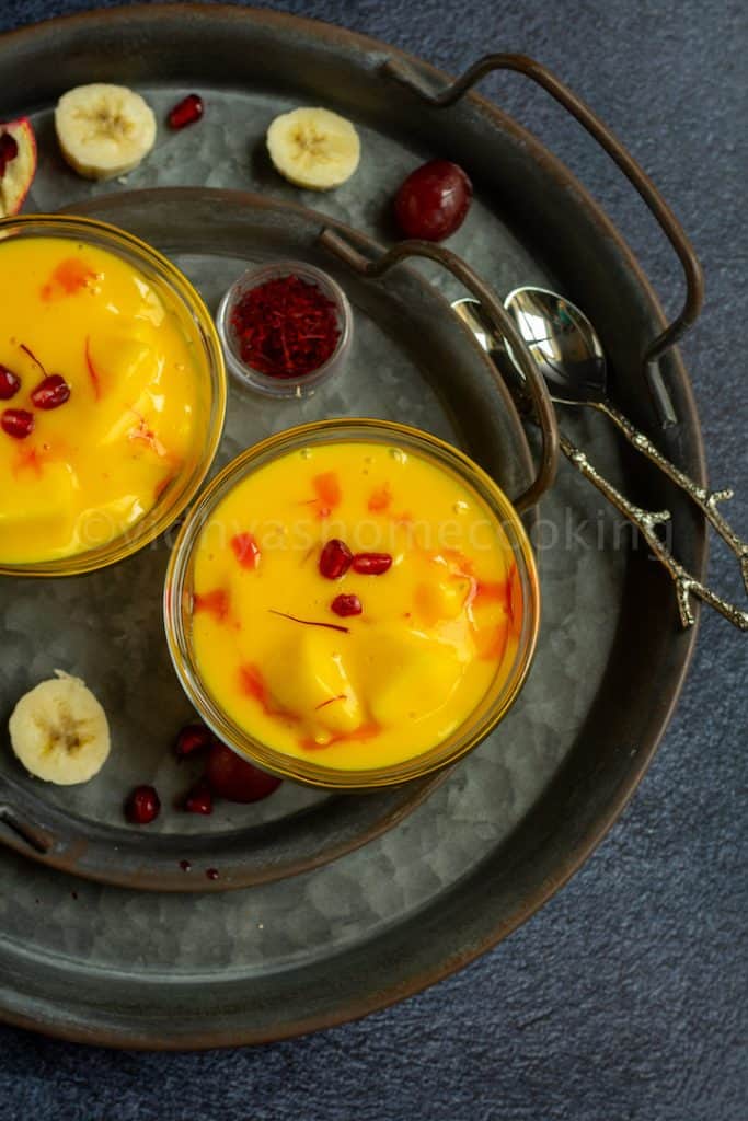 overhead shot of fruit custard served in two bowls with fruits on the side